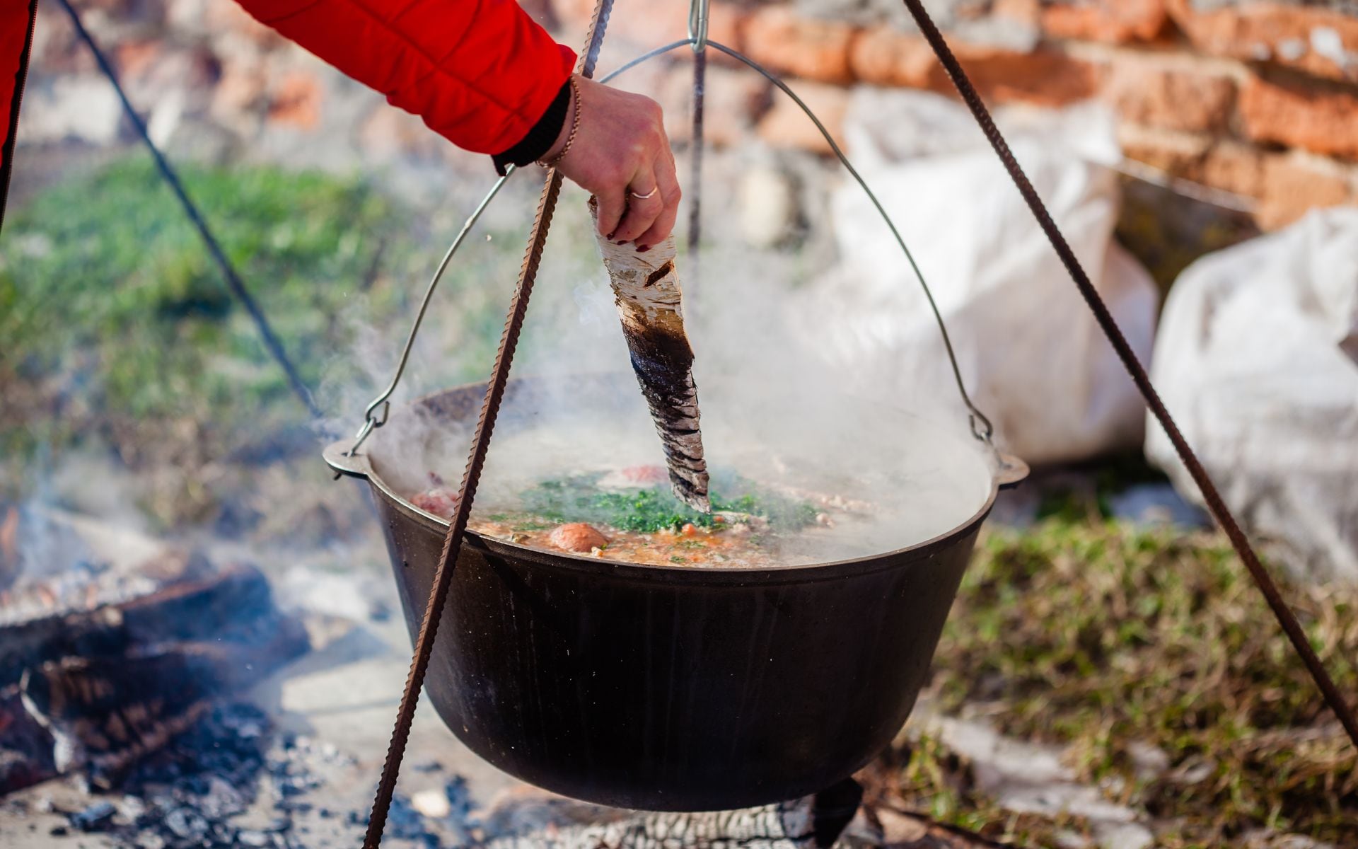 Outdoor fish boil kettle over a roaring wood fire at dusk in Fish Creek, Door County, Wisconsin, with guests gathered around watching the boilover