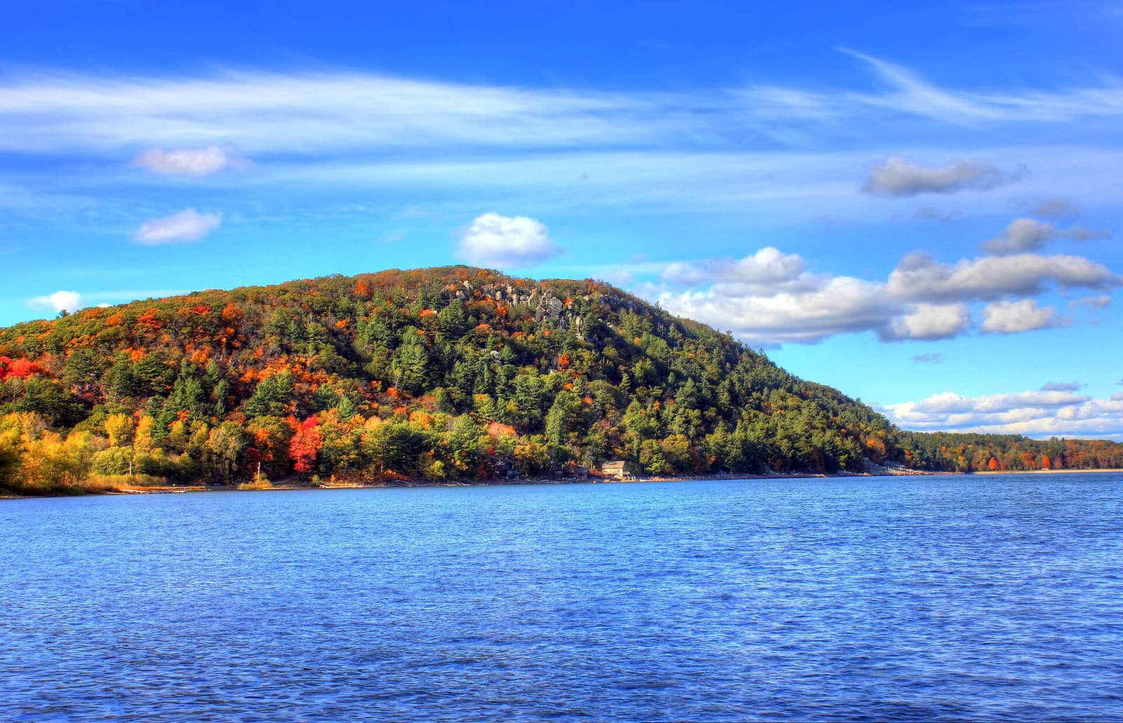 Autumn-colored quartzite bluff rising above the blue water of Devil's Lake at Devil's Lake State Park near Baraboo, Wisconsin